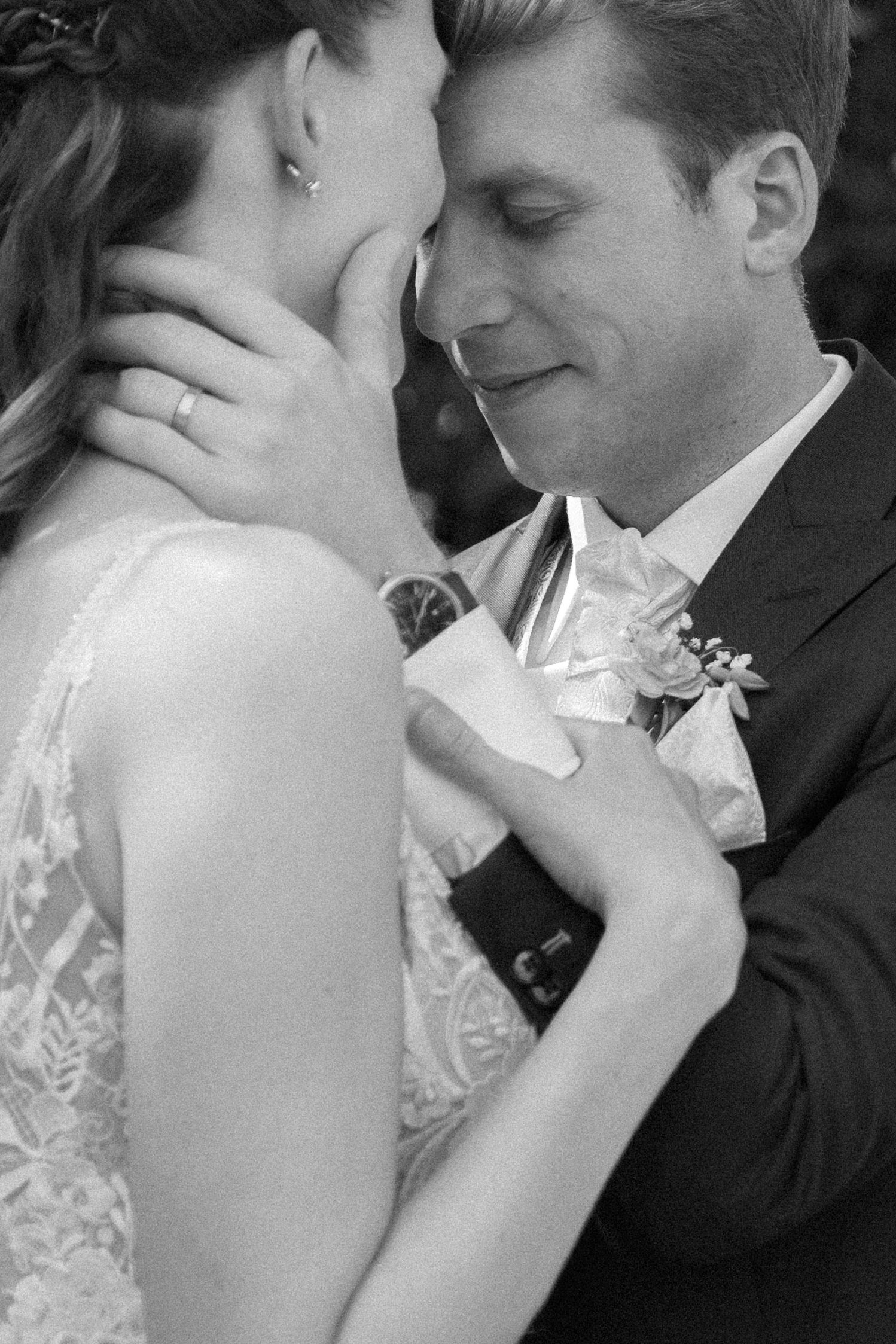 A bride and groom forehead to forehead in a quiet wedding-day moment, in black and white