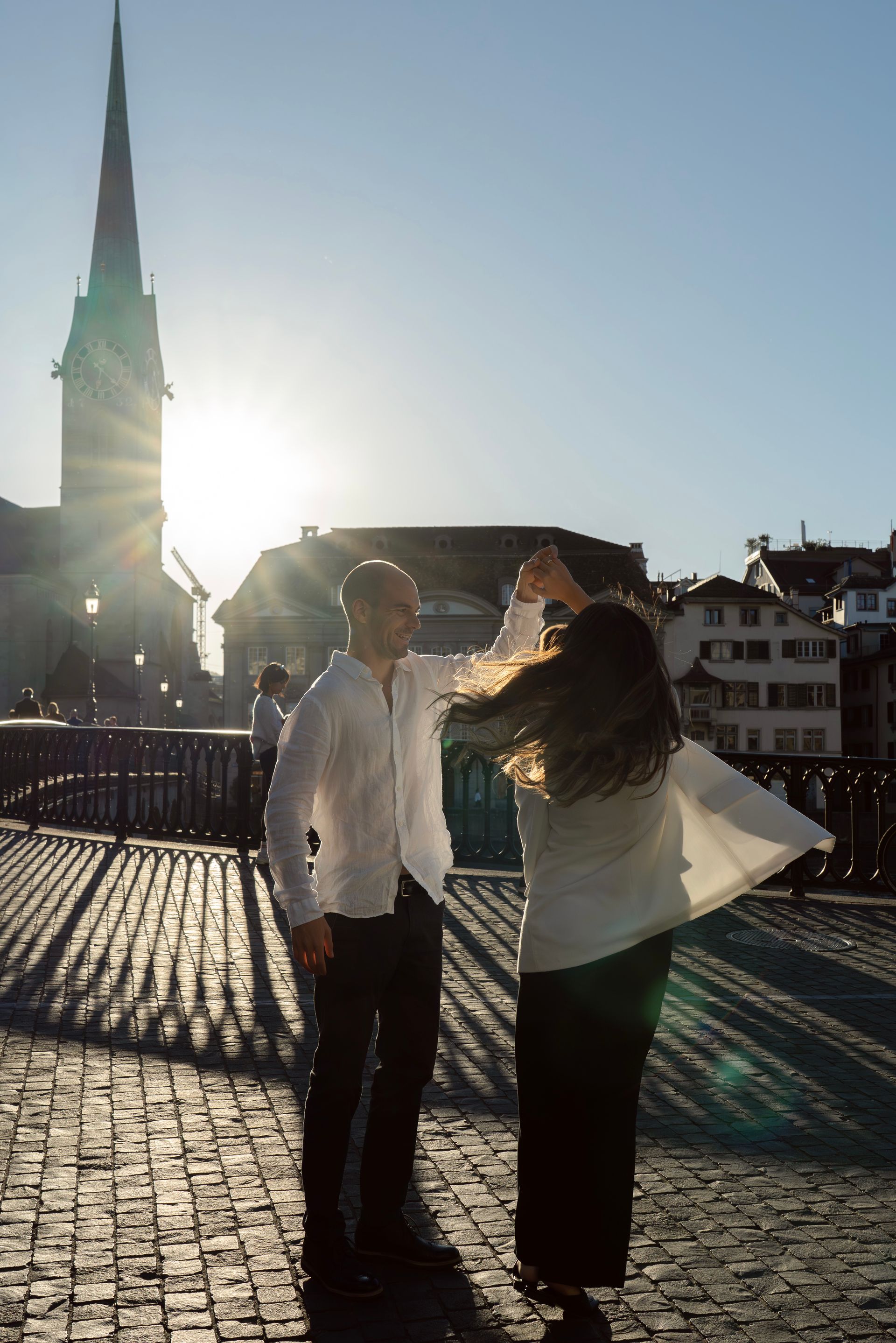 A couple dancing on a cobbled bridge at sunset