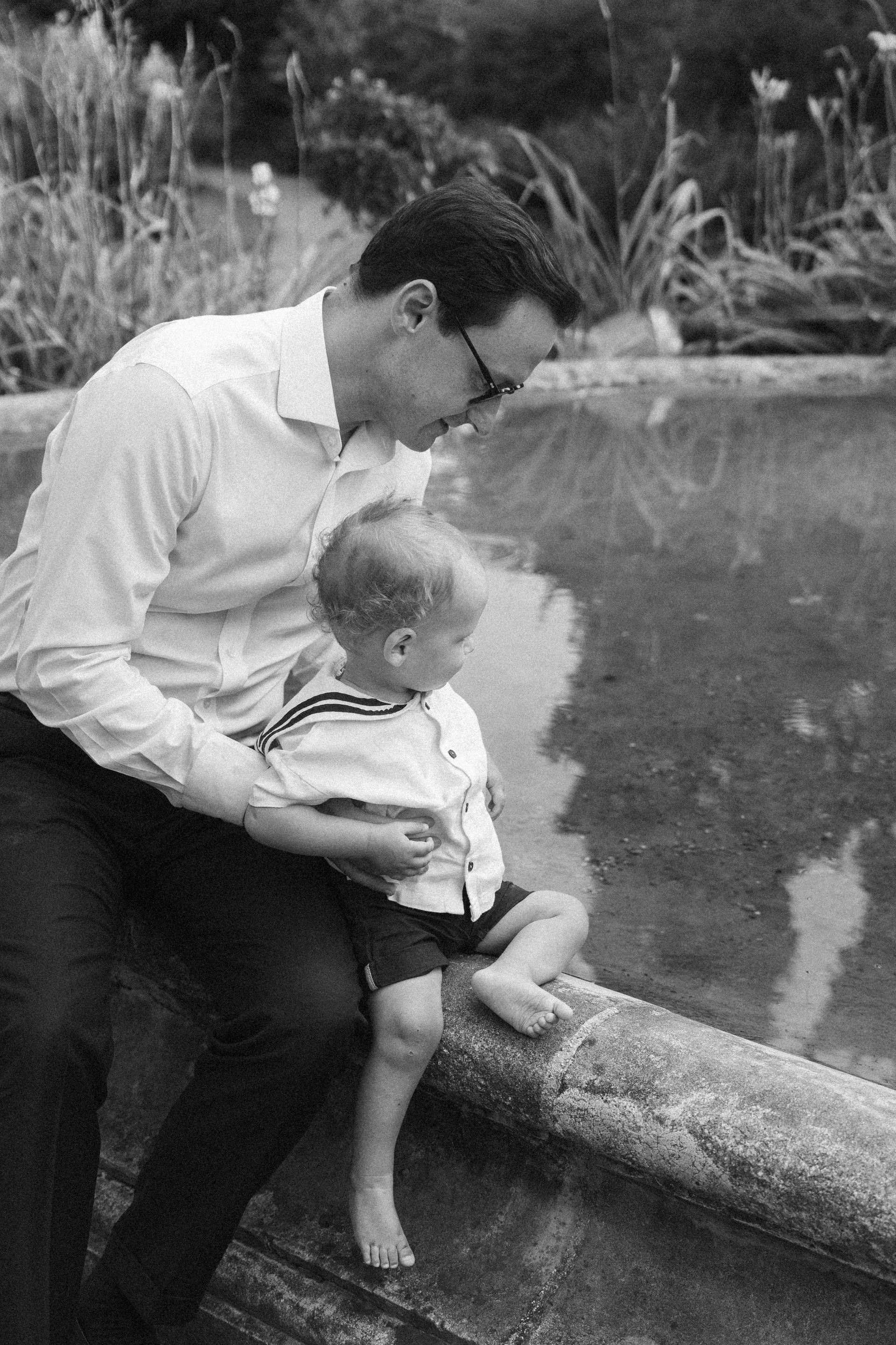 A father and son beside a garden pond, in black and white
