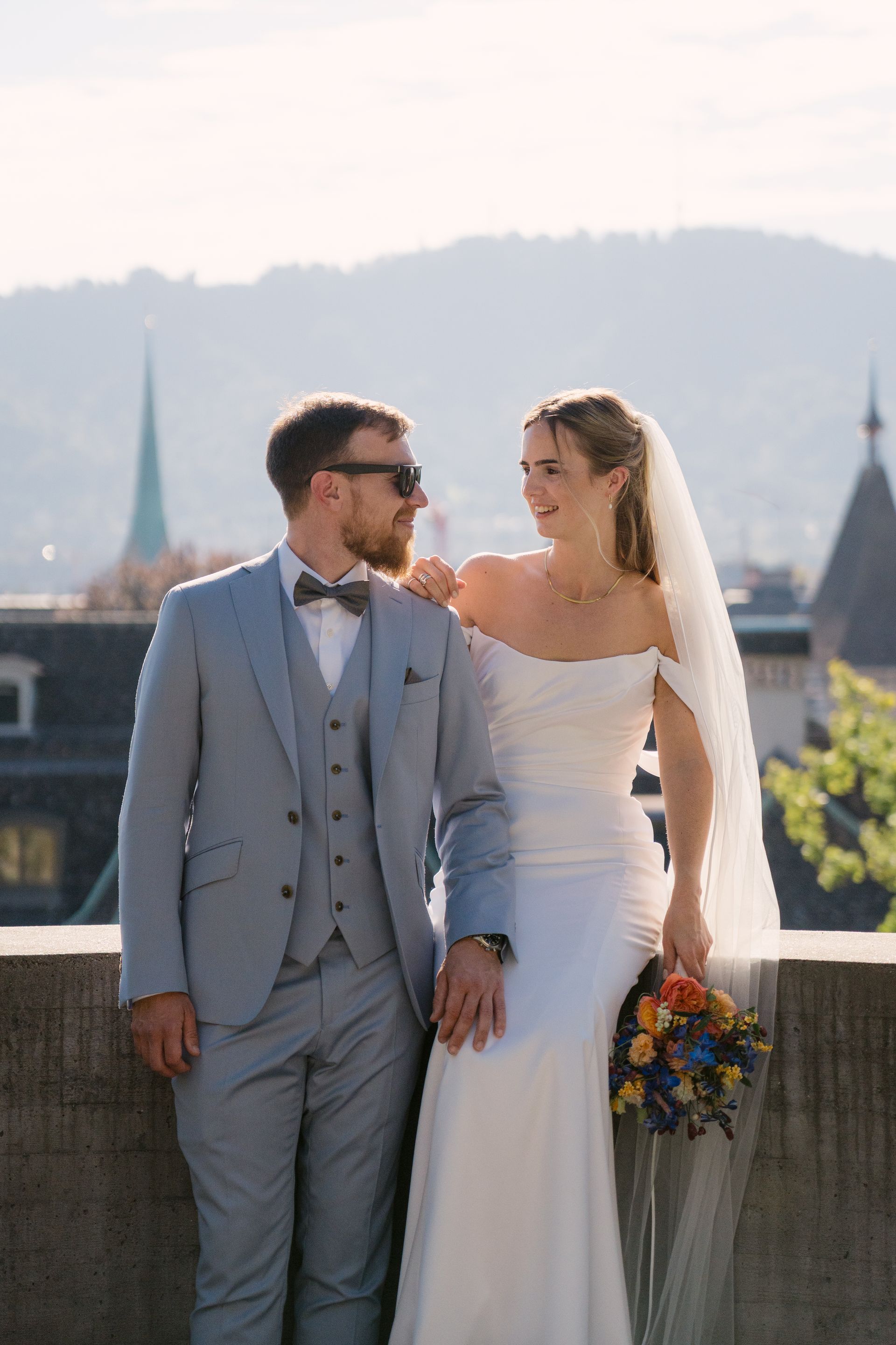 A bride and groom looking at each other with the city skyline behind them