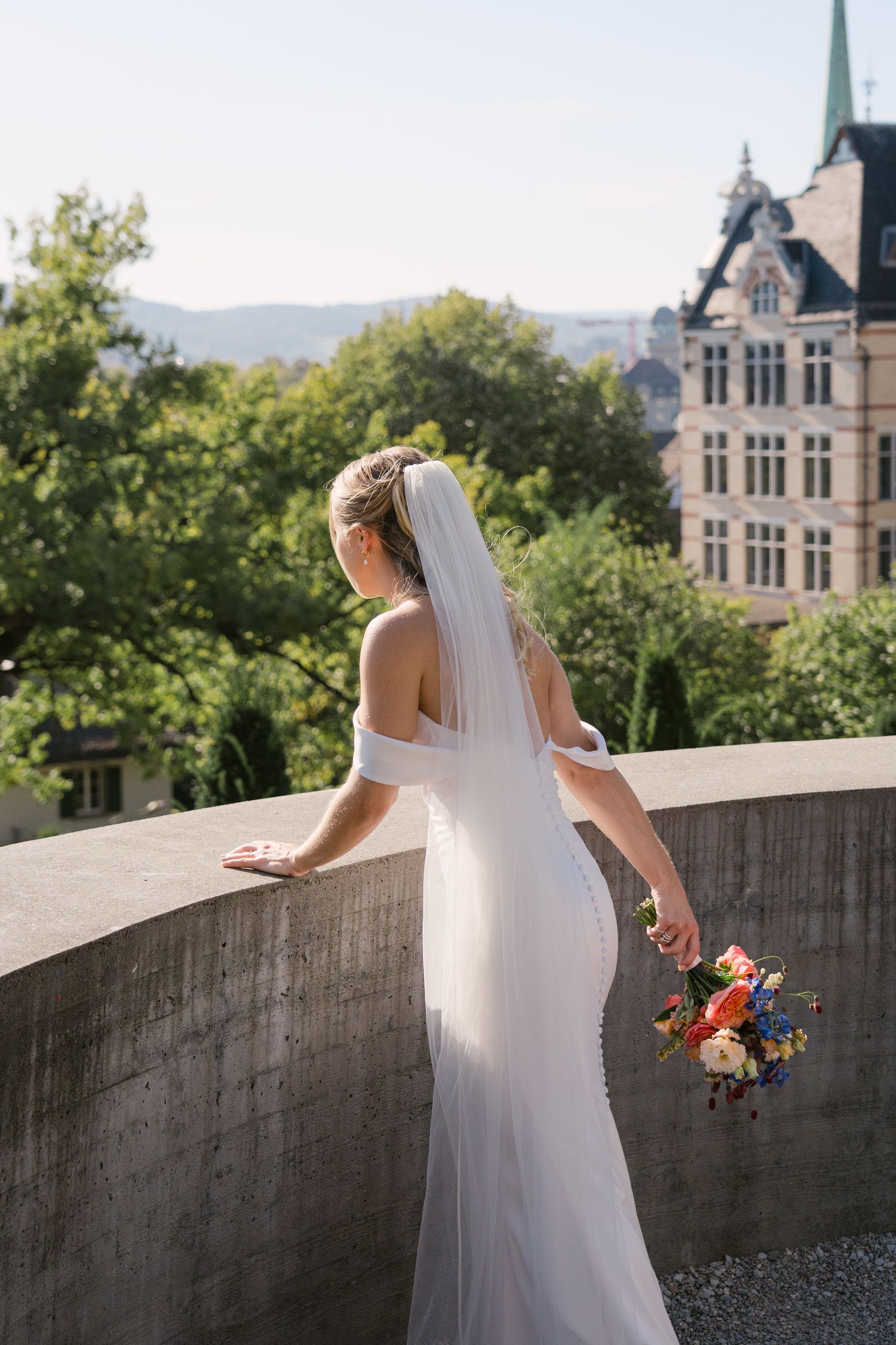 A bride looking out holding a flower bouquet